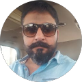 Man with sunglasses and beard in car.
